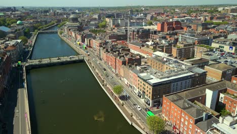 wide, forward travelling erial video of the river liffey, and the ha'penny bridge in dublin city centre, ireland on a bright and sunny day. filmed in 4k, 60fps and with rec709 color.