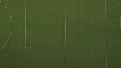 vista aérea de un gran campo deportivo verde que se mueve más cerca del campo hasta que se puede ver el césped artificial