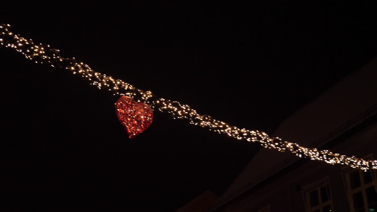 Christmas and New Year decorations of lights in a heart strung across main street in a town - night