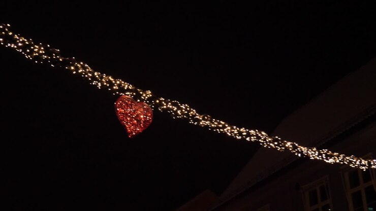 Christmas and New Year decorations of lights in a heart strung across main street in a town - night