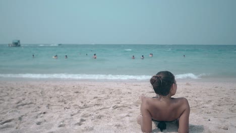 brunette-in-black-bikini-with-open-shoulders-lies-on-beach