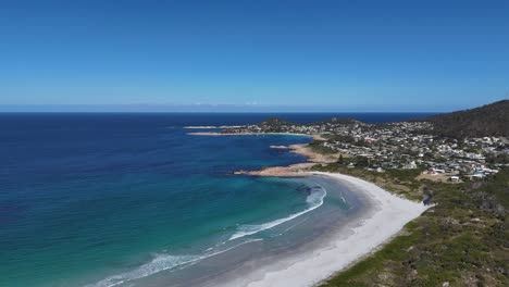 aerial flight along sandy beach of tasmania with bicheno town in background