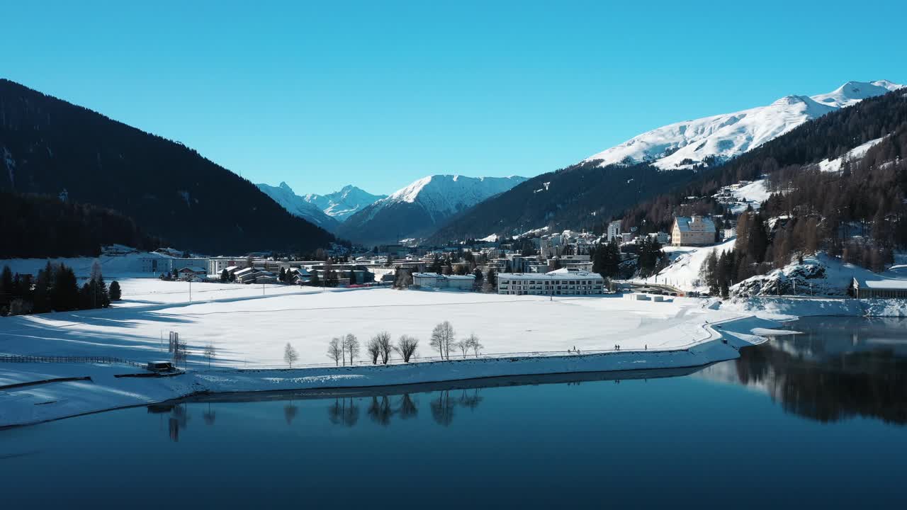 excelente vista aérea acercándose al nevado davos, suiza sobre un lago
