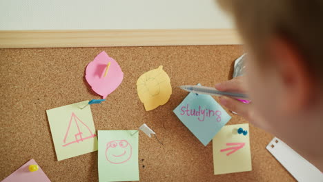 Boy-draws-sun-on-piece-of-colored-paper-in-shape-of-leaf