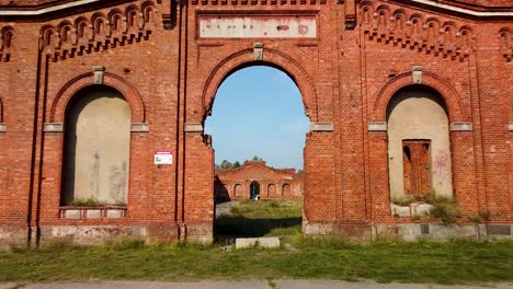 Aerial-view-of-former-russian-tsar-army-gymnastics-hall-in-Karosta,-Liepaja,-used-for-gymnastics-performances-and-competitions-for-horseback-riders,-wide-low-angle-drone-shot-moving-forward