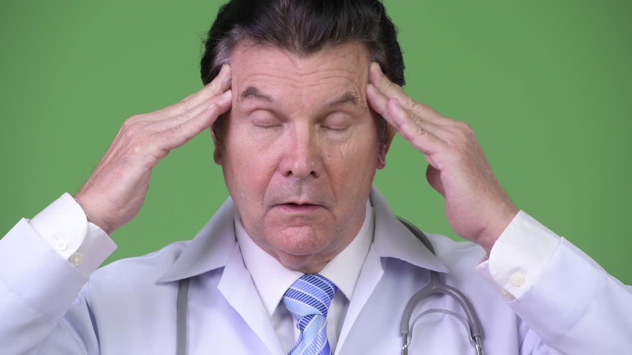 Senior handsome man doctor having headache