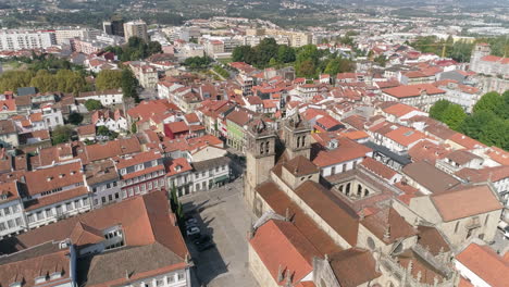 overflying the red roof buildings in the city of braga towards the historic braga cathedral on a sunny day in portugal