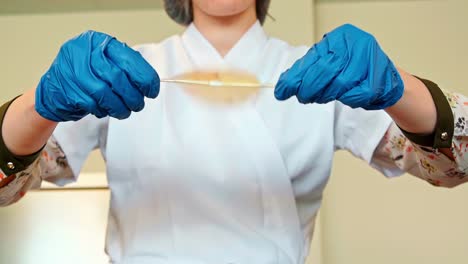 gloved worker spins sealed orange liquid bag in lab or sterile food safe environment