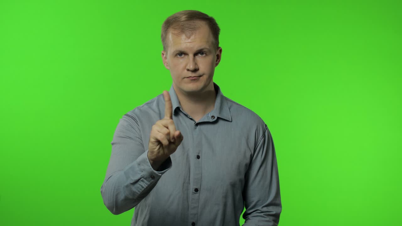 Muž varuje napomínajícím gestem prstu, říká 'ne', 'buď opatrný', znamení nesouhlasu. Chroma key.