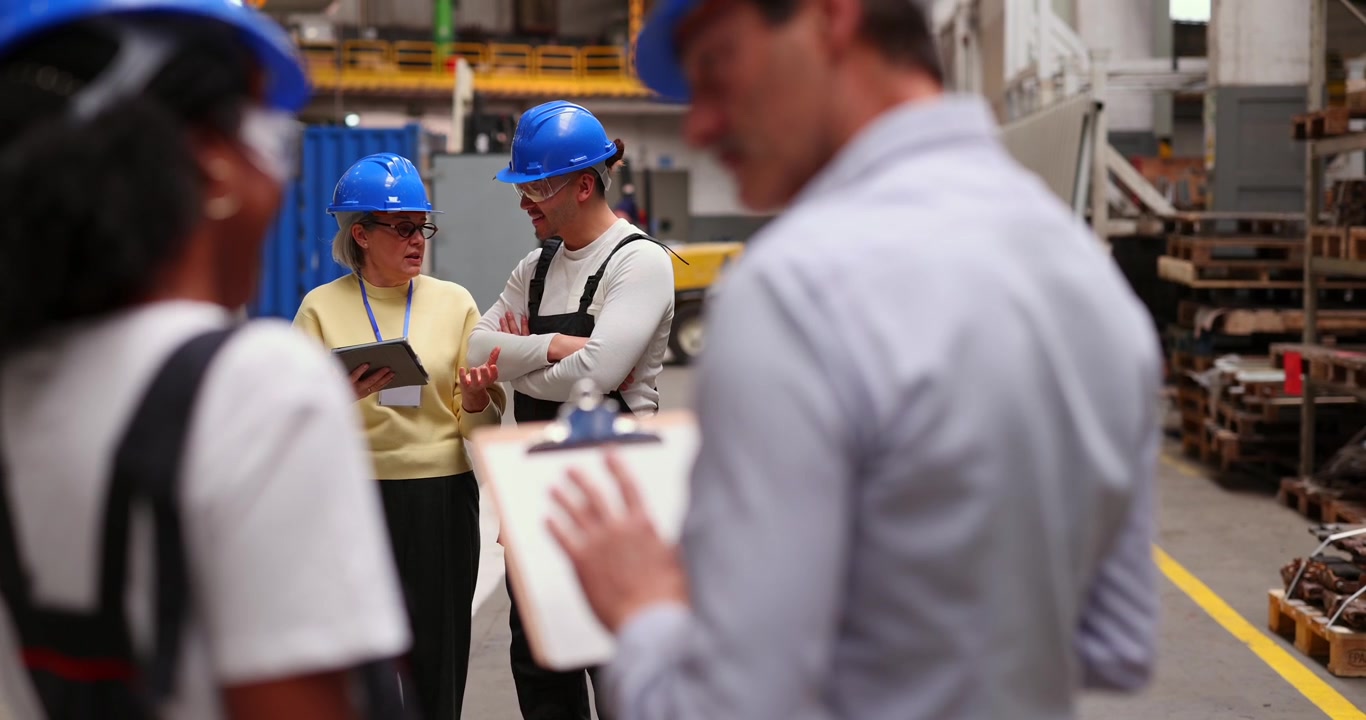 Equipo diverso de trabajadores industriales discutiendo un proyecto en una fábrica