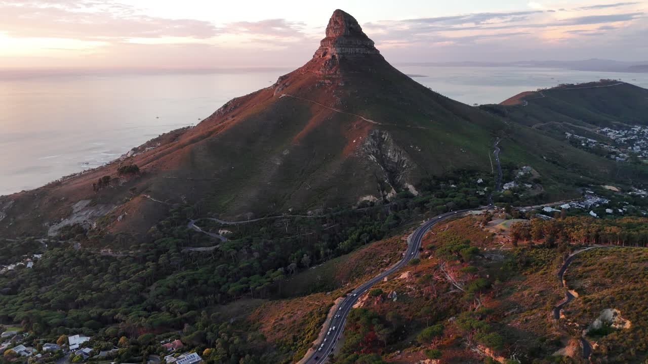 drone close to Lion’s Head mountain at sunset with Atlantic Ocean coastline aerial shot over Camps Bay beach South Africa travel destination