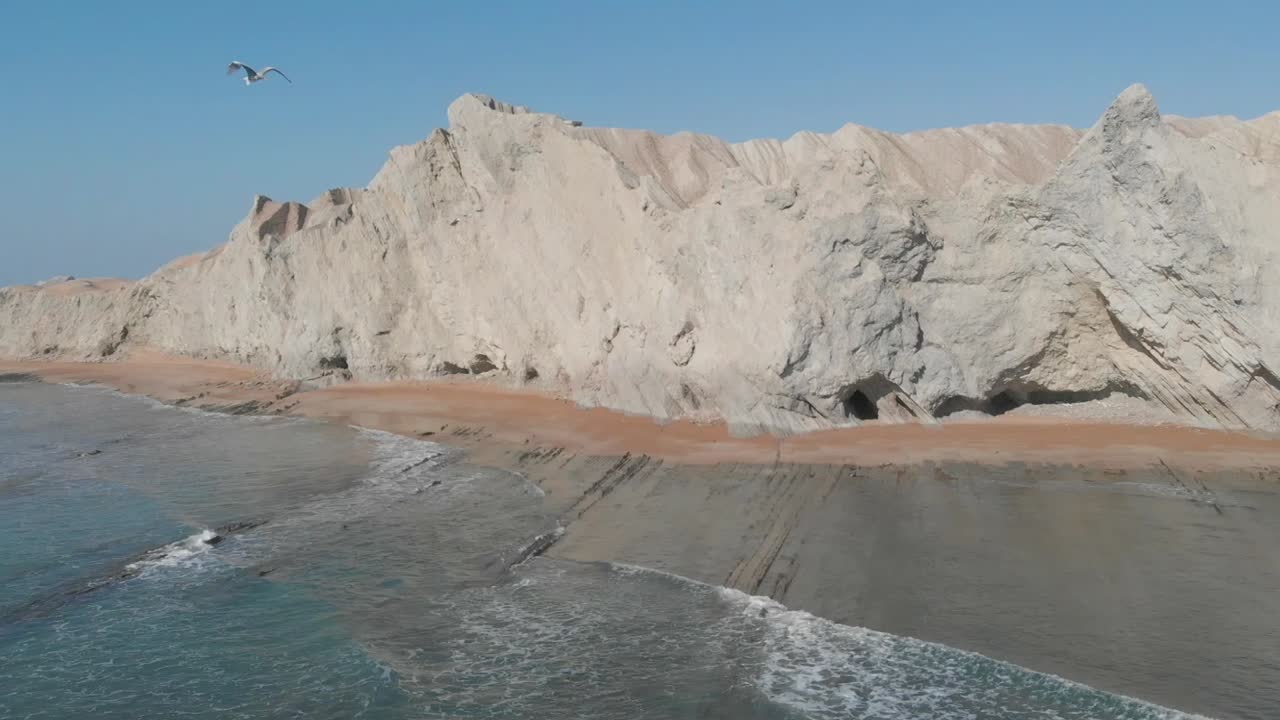 las olas del mar están rompiendo en la montaña y los pájaros están volando sobre este