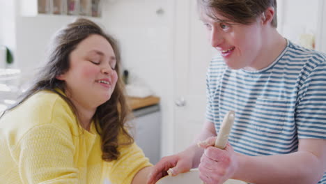 young downs syndrome couple mixing ingredients for cake recipe they are baking in kitchen at home