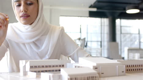 Architect working on building model in office, focusing on design details, copy space