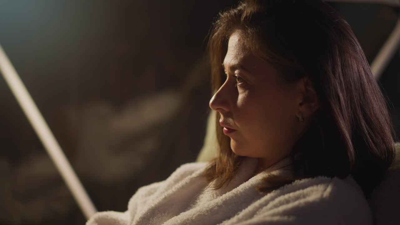 Woman looking out of window on calm night overcomes by sense of melancholy and feels pain of loneliness. Lonely female calms down and relaxes closeup