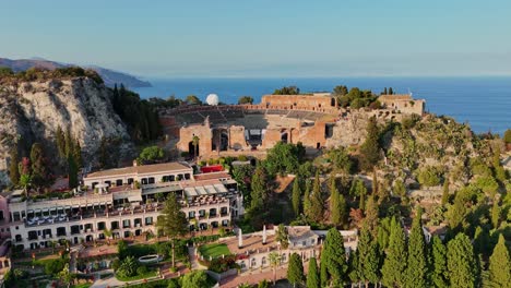 Taormina,-Italien-Mit-üppigem-Grün-Und-Historischer-Architektur,-Küste-Sichtbar,-Luftaufnahme