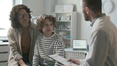 mother and child talking to doctor during medical consultation in clinic