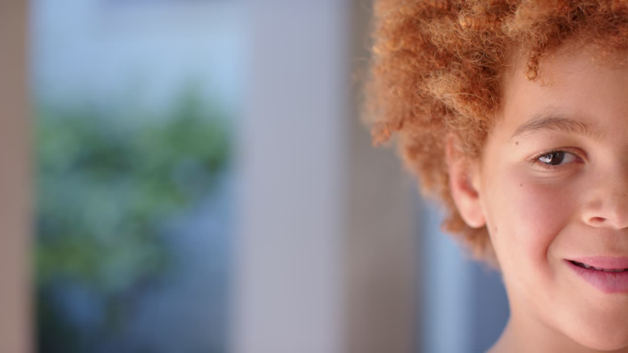 African American boy shifting into frame by window showing curly hair smiling responding to cue