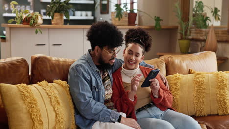 couple sitting on a couch looking at a smartphone