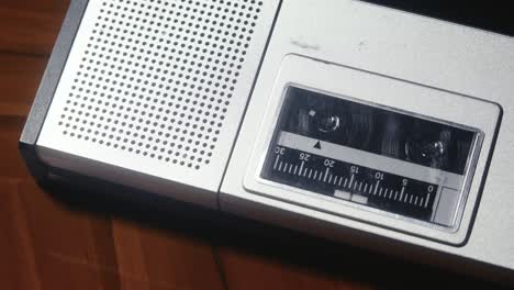 close-up view of a vintage cassette player lying on a wooden table top, with a cassette playing