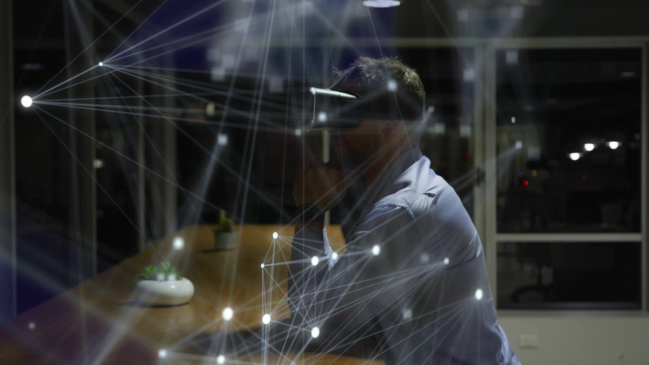 Uomo con cuffie al tavolo che alza la mano e avvia un overlay di rete in crescita per test tecnologici