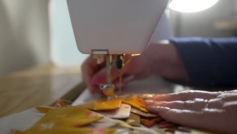 skilled homemaker sewing quilt scraps into a potholder - isolated orange scraps series