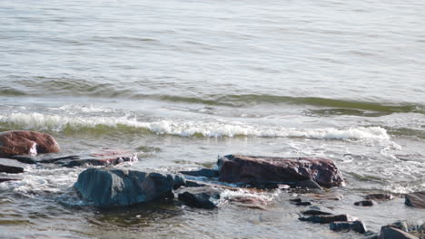 Foamy-sea-waves-crashing-on-rock-while-washing-up-rocky-seashore