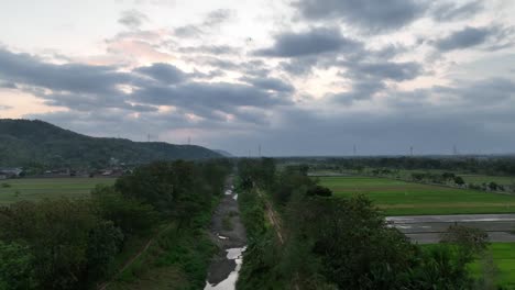 Drone-flight-over-partially-dried-up-river-bed-in-early-evening