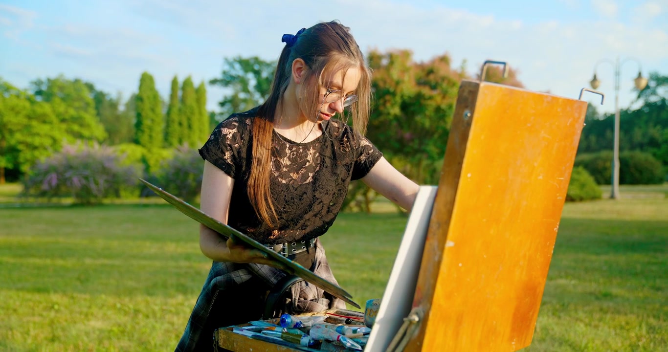 Young Woman Mixing Paints on Palette Knife Outdoors