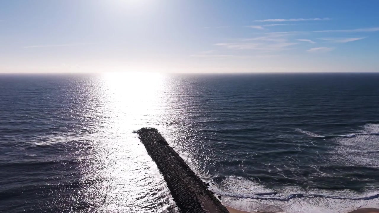 Aerea - Frangiflutti in pietra che si estende nell'oceano al tramonto.
