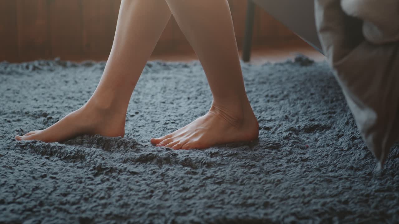Barefoot feet on a gray carpet in a bedroom