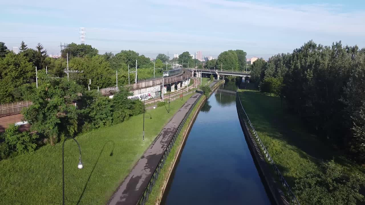 tren de pasajeros montando en la curva de la vía en la ciudad de milán cerca del canal de agua, vista aérea
