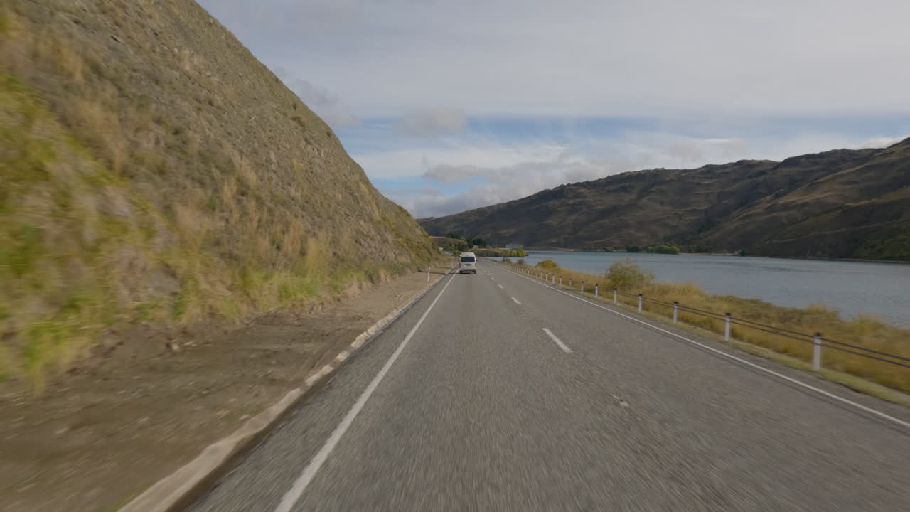 pov conduciendo un coche en la carretera que pasa por la presa de clyde en clyde, otago, nueva zelanda