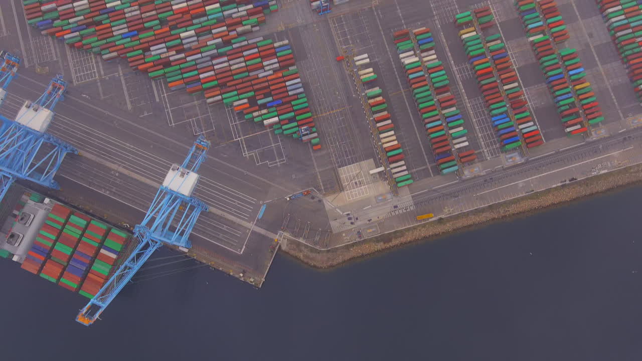 Misty clouds and fog over the San Pedro Port with shipping containers ready to be loaded on cargo ships during a supply chain crisis - tilt up aerial reveal