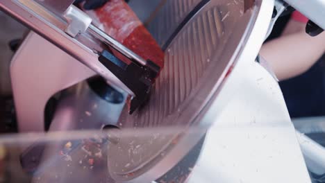 butcher cutting spanish chorizo with a slicing machine