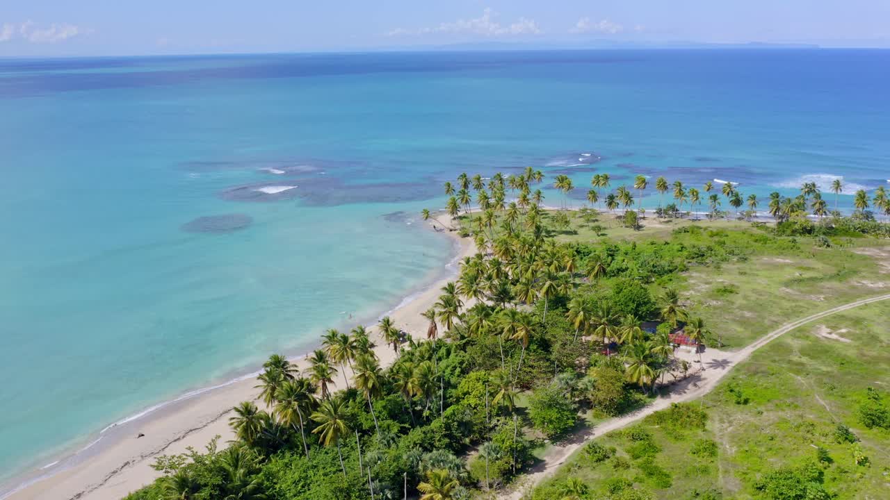 Vista aérea de palmeiras e águas rasas azul-turquesa na Playa Costa Esmeralda, em Miches, República Dominicana - filmagem de drone.