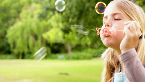 Cute-little-girl-blowing-bubbles-in-park