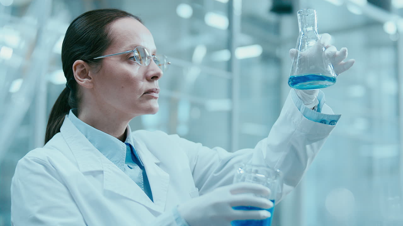 Female Chemist Examining Blue Liquid in Flask during Laboratory Experiment