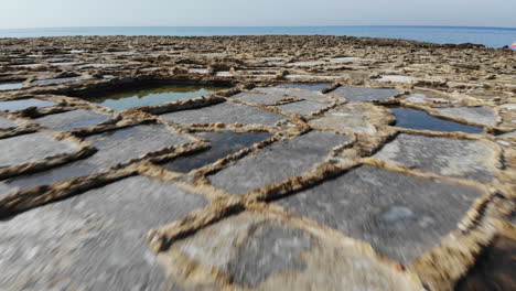 an aerial low-altitude drone fly over of the salt pans on the island of gozo in malta