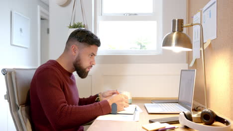 working from home, man drinking coffee and using laptop at desk