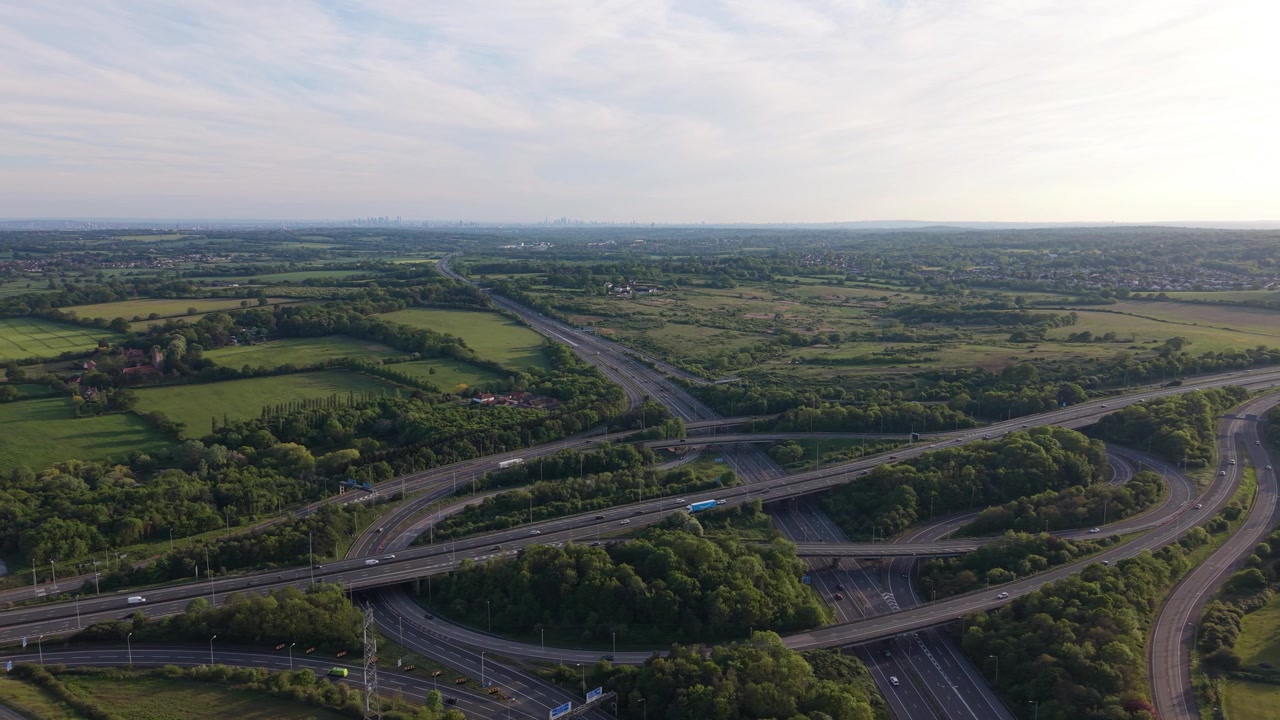 Elevated view showing a busy motorway interchange in England. Cars and trucks actively traverse the numerous lanes and connecting bridges.