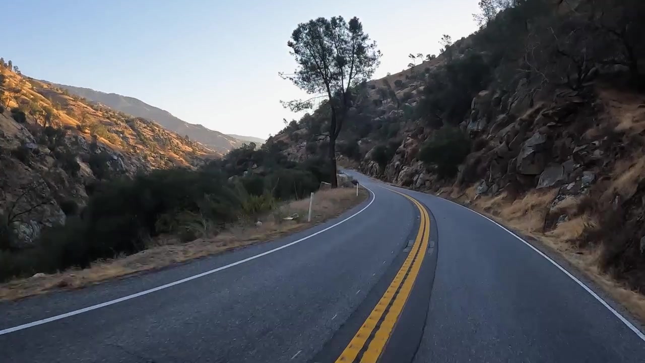 Luce del sole all'ora d'oro illumina una valle fluviale aspra e panoramica, POV dall'autostrada