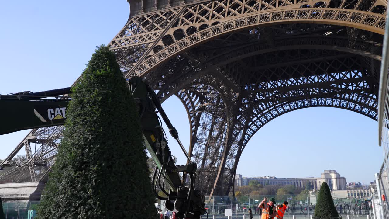 Construction crews work beneath the Eiffel Tower post-Olympics games on a sunny day, showcasing urban renovation in Paris, in slow motion