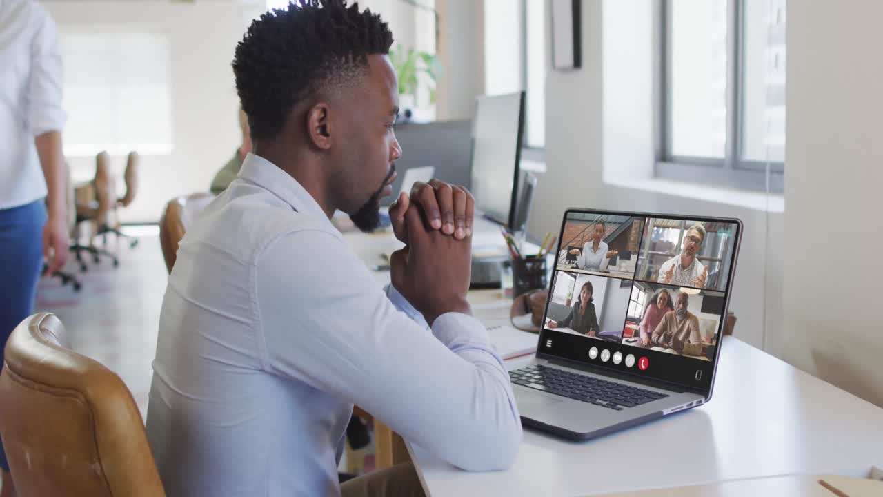 African american man using laptop for video call, with diverse business colleagues on screen