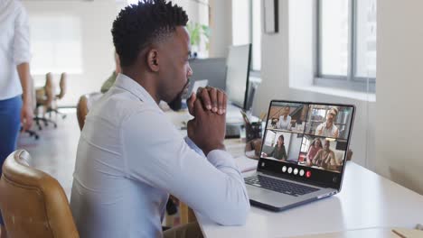 african american man using laptop for video call, with diverse business colleagues on screen