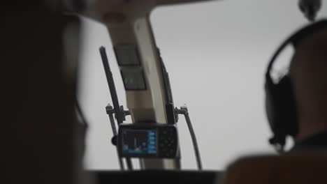 a pilot wearing a headset flying a helicopter in poor visibility