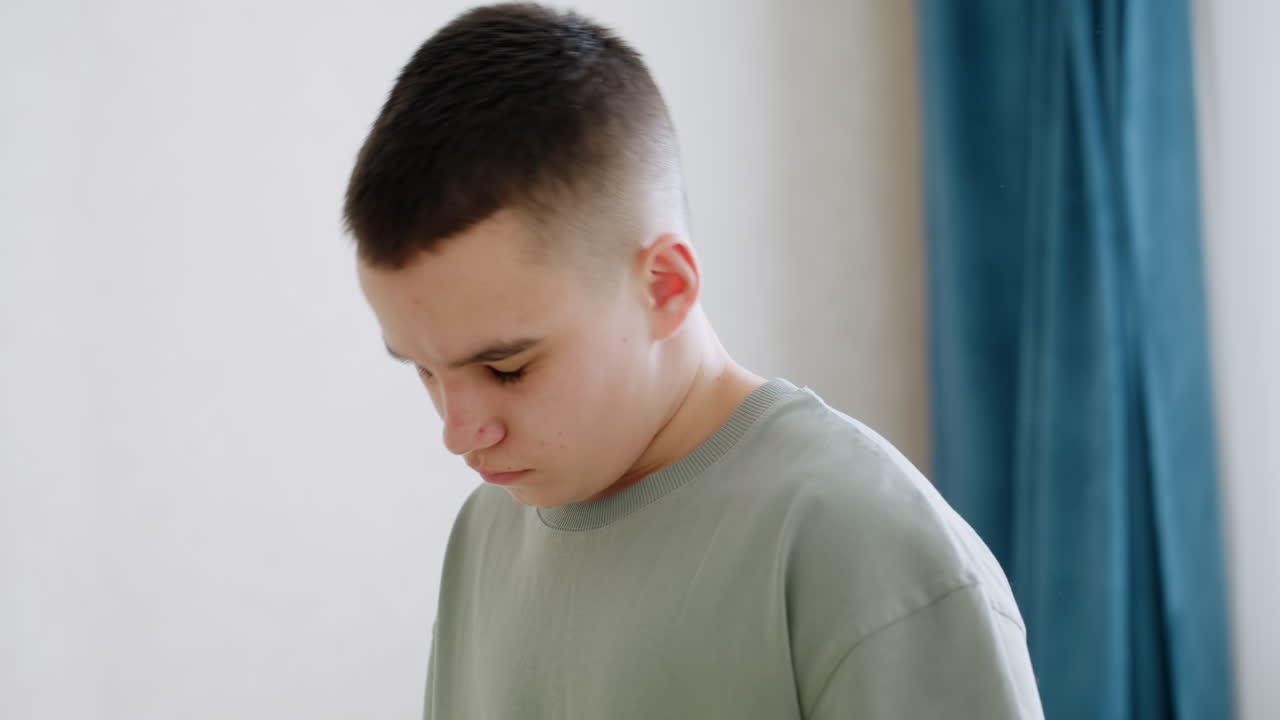 Close up of boy tilting head backward while performing neck stretch during flexibility training in softly lit home environment, intent posture shows effort and balance