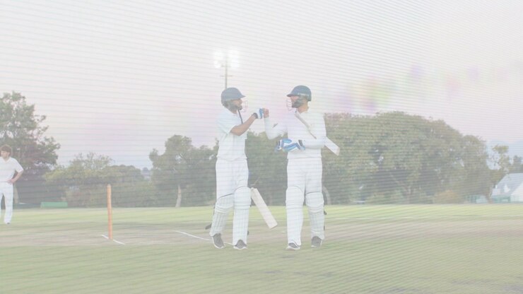 Battitori di cricket che parlano, si battono il pugno dopo un traguardo, tenendo caschi e mazze mentre lasciano il campo.