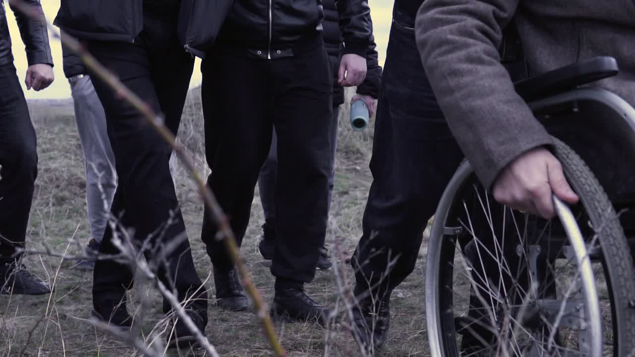 группа людей, идущих с человеком в инвалидной коляске