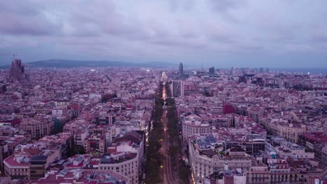 Barcelona-Al-Atardecer-Con-Las-Luces-De-La-Ciudad-Empezando-A-Brillar,-Vista-Aérea